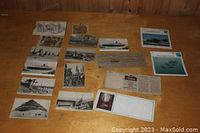 Overview of the collection spread on a wooden surface showing various postcards including ships, aircraft, pyramids, and street scenes.