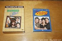 Married with Children Complete Series and Seinfeld Seasons 1 & 2 DVD box sets on wooden surface.