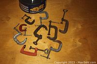 Photo showing ten small C-clamps in various sizes and finishes on wooden surface