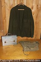 Photo showing the green shirt on a hanger, the metal lunch box, and the green bag on a wooden surface.