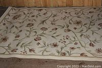 Full view of the white floral area rug on wooden floor with detailed pattern in muted tones.