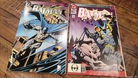 Photo showing both Batman #500 comics side-by-side, die cut foil cover on the left, regular cover on the right, displayed on a wooden surface.