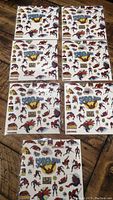 Photo of six sheets of Spiderman stickers arranged on a floor, showing colorful classic comic book style artwork and logos on each sheet