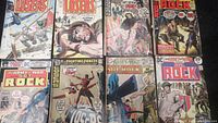 Photo showing all eight vintage war comics from DC Comics laid out on a surface, including The Losers and Sgt. Rock titles.