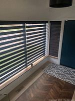 Corner view showing two large black zebra blinds lowered over windows.