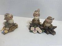 Group photo showing both figurines placed on a white surface, depicting Thumper and Thumper's sisters in cheerful poses with flower and log bases.