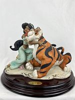Front view of porcelain sculpture showing Jasmine hugging Rajah on wooden base with Florence plaque