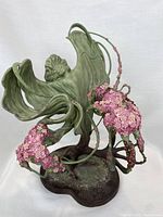 Front angle showing green sprite figure with flowing leaf wings and pink flower clusters on green vines, mounted on brown base.