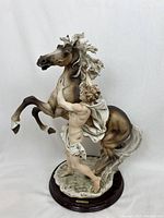 Porcelain figurine front view showing male figure and rearing horse mounted on wooden base