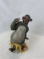 Front view of Baloo figurine showing joyful pose and grass skirt.