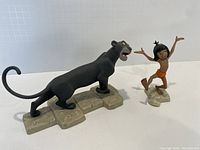Mowgli and Bagheera figurines side by side on white background showing their size and details.