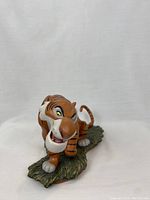 Front view of orange and black striped Shere Khan resin sculpture on green base