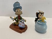 Front view of both Jiminy Cricket and Figaro & Cleo figurines placed side by side on a white background.