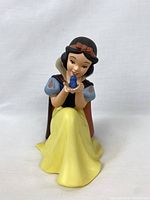 Front view photo of the Snow White figurine holding a blue bird, showing costume colors and pose.