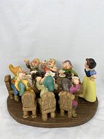 Side view of full figurine showing Snow White and dwarfs at table