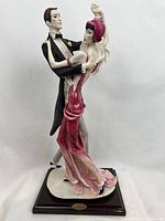 Front view of the dancing couple figurine in pink and black on wooden base