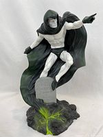 Full frontal view of The Spectre statue showing the figure in an active pose with flowing cape and stone base with tombstone.