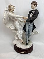 Front view of porcelain bride and groom dancing figurine on wooden base