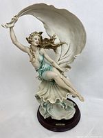 Front view of Wind Song sculpture on wood base showing figure in teal drapery and billowing cloak