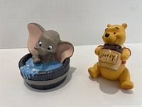 Winnie the Pooh and Dumbo sculptures side by side, showing detail and scale.
