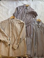 Three men's button-up shirts laid out flat showing overall appearance including colors and cuffs.