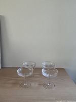 Four Ferm Living champagne coupes displayed on a wooden surface showing ridged detail on the bowls.