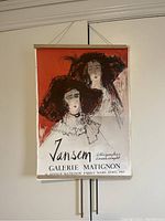 Front view of the Jansen Galerie Matignon art poster depicting two women in hats with exhibition details and hung on a wall with string.