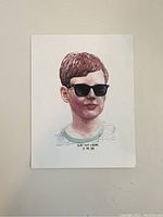 Photo of a non-framed print showing a young boy with reddish hair wearing black sunglasses and a striped shirt with text beneath.