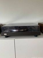 Front view of turntable on white cabinet with dust cover down