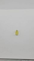 Small pear-shaped lemon citrine gemstone on a white background, showing overall size and color.