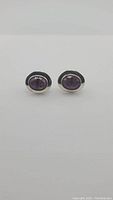 Front view of the pair of earrings showing the deep purple oval-shaped amethyst set in sterling silver.