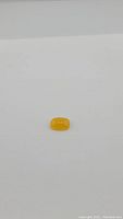 Top-down view of the honey jade cabochon showing smooth cushion shape and rich honey yellow color against a plain white background.