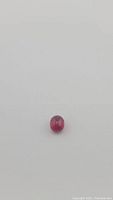 Front view of oval cabochon ruby gemstone showing strong red coloring and smooth polished surface.
