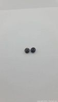 Pair of oval cut black onyx gemstones on white background showing checkerboard faceted surfaces and caramel tints on one stone.