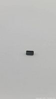Photo of a natural green tourmaline gemstone against a white background, small size approx 9.2x5.2mm, octagon cut showing facets and color.