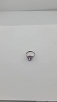 Full view of adjustable silver ring with purple amethyst gemstone on white background.