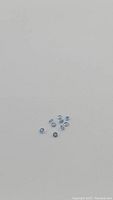 Photo of multiple natural light blue sapphires scattered on a white background, showing overall parcel.