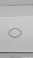 Full view of natural Chrysoprase beaded stretchy bracelet lying in a circular shape on white background.