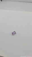 Photo showing rectangular emerald cut ametrine gemstone on a white background, highlighting its dual color and facets.
