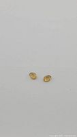 Pair of small oval cut golden citrine gemstones on a grey background.