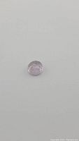 Front view of hand carved light pink purple amethyst gemstone showing smooth polished surface and floral carving details.