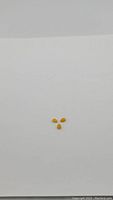 Three small pear-shaped natural honey jade cabochon stones arranged on a white background.