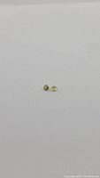 Pair of small round cut sphene gemstones against white background, showing size and shape.