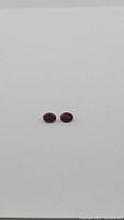 Front view of the matched pair of natural cherry red garnet gemstones showing color and size difference