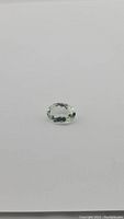 Oval-cut natural prasiolite gemstone shown from a side angle on a plain white background.