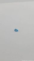 1.59 carat pear cut Swiss blue topaz gemstone displayed on a white background, showing clarity and color.