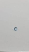 Photo of single round cut sky blue topaz gemstone on plain grey background