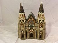 Front view of the unlit cathedral figurine showing detailed twin towers, windows, and central archway.