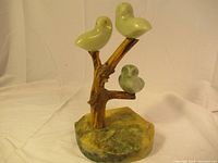 Full view of the jade owl bird sculpture set on a carved naturalistic base.
