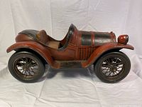 Side profile of the large vintage replica car showing the red body, black hood, and single ribbed seating